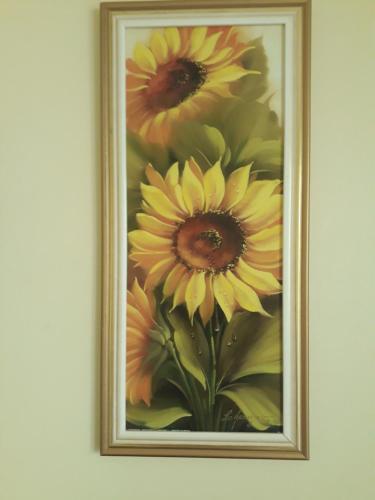 a painting of yellow flowers in a frame on a wall at Aluguel Temporada em Gramado in Gramado