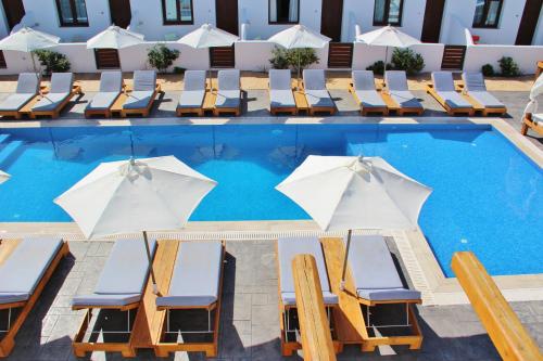 a swimming pool with chairs and umbrellas at Ifestos Villa in Fira
