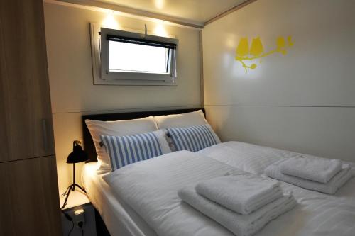 a bedroom with a white bed with towels on it at Cozy floating boatlodge "Maastricht". in Maastricht