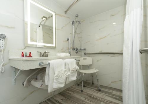 a white bathroom with a sink and a shower at SureStay Plus Hotel by Best Western Sacramento Cal Expo in Sacramento