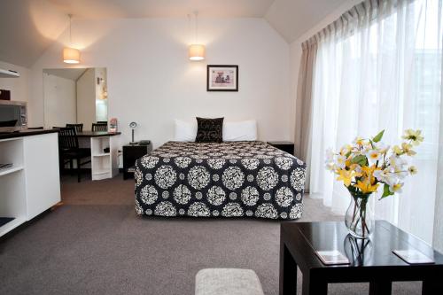 um quarto de hotel com uma cama e uma mesa com flores em Cable Court Motel em Dunedin