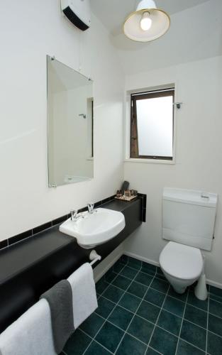a bathroom with a sink and a toilet and a mirror at Cable Court Motel in Dunedin