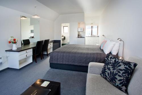 a bedroom with a bed and a desk and a couch at Cable Court Motel in Dunedin