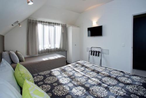 a bedroom with a large bed and a television at Cable Court Motel in Dunedin