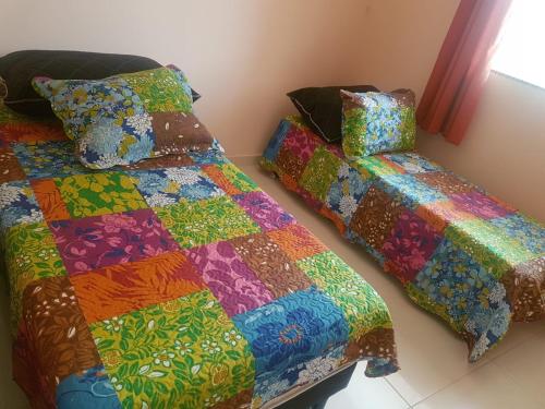 - 2 lits dans une chambre dotée d'une couette colorée dans l'établissement Flat - Coroa Vermelha, à Santa Cruz Cabrália