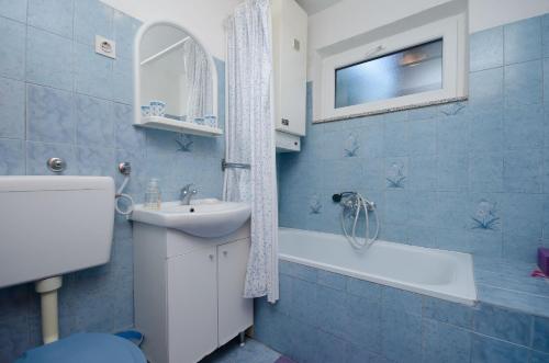 a blue tiled bathroom with a sink and a bath tub at Apartments Jasminka in Selce
