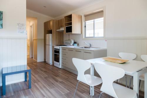 a kitchen with a white table and white chairs at McLean Beach Holiday Park in Deniliquin
