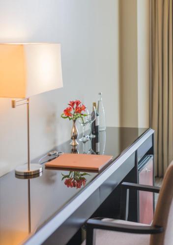 a desk with a lamp and a vase with flowers on it at Delfines Hotel & Convention Center in Lima