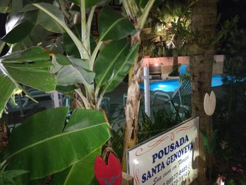 a sign in front of a plant with a pool at Pousada Santa Genoveva campeche in Florianópolis