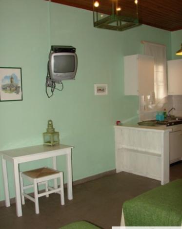 a kitchen with a table and a tv on the wall at Harry's Studios 1 in Gaios