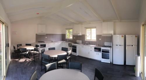 a large kitchen with white appliances and tables and chairs at Warburton Holiday Park in Warburton