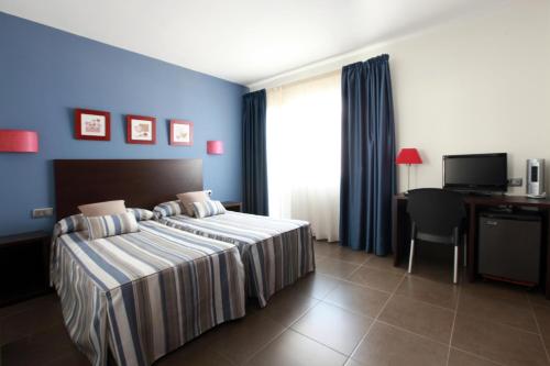 a hotel room with a bed and a desk with a computer at Hotel Marblau Tossa in Tossa de Mar