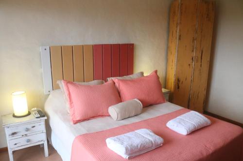 a bedroom with a bed with pink and white pillows at Posada de la Viuda in Punta Del Diablo