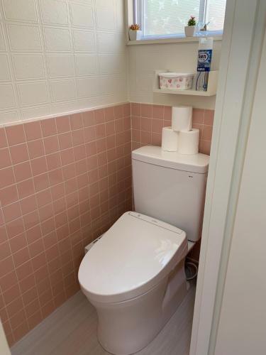a bathroom with a toilet with pink tiles at Sai's House Hakuba in Hakuba