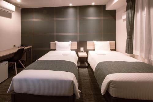 a hotel room with two beds and a desk at Kuretake-Inn Hamamatsueki Minamiguchi Premium in Hamamatsu