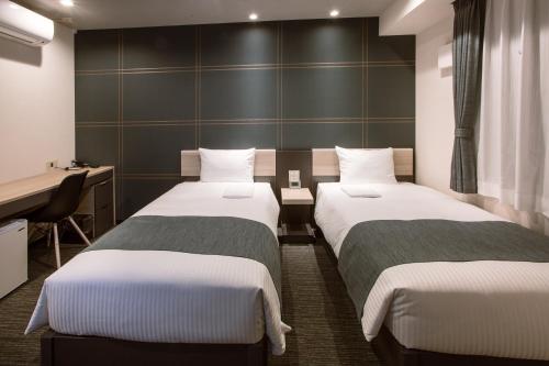 a hotel room with two beds and a desk at Kuretake-Inn Hamamatsueki Minamiguchi Premium in Hamamatsu