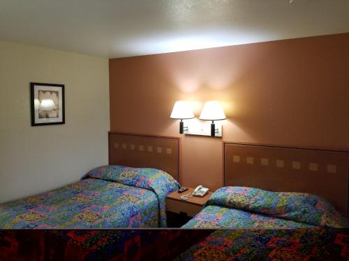 ein Hotelzimmer mit zwei Betten und zwei Lampen in der Unterkunft America's Best Inn - Macon in Macon