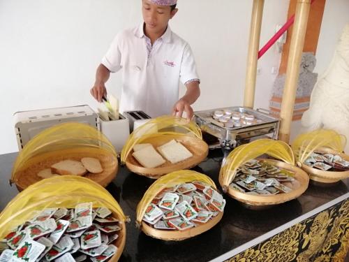 a man standing next to a table with baskets of food at Swastika Bungalows in Sanur
