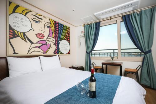 1 dormitorio con 1 botella de vino en la cama en Hu An Stay Hotel, en Seogwipo