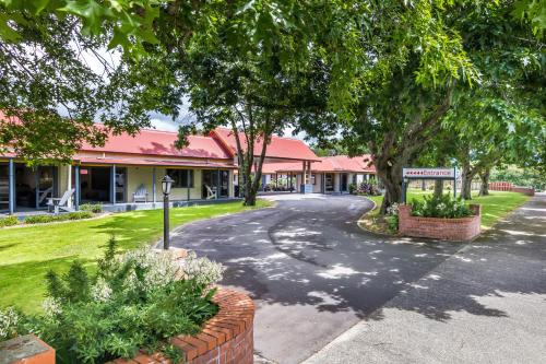 a street in front of a building with trees at ASURE Oak Estate Motor Lodge in Greytown