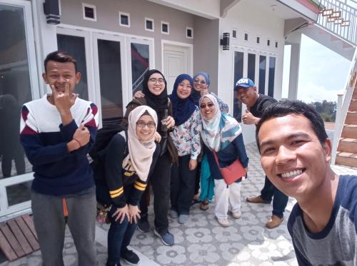 a group of people posing for a picture in front of a house at Bromo Otix Guest House in Bromo