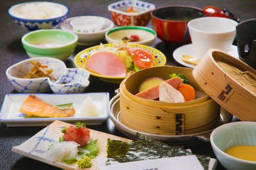 una mesa cubierta con tazones y platos de comida en New Ogiya, en Fukushima