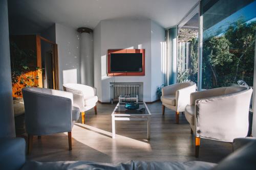 sala de estar con muebles blancos y TV de pantalla plana en Hosteria Los Tilos en Villa Carlos Paz