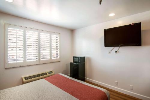 a bedroom with a bed and a flat screen tv on the wall at Motel 6 Monterey Park in Monterey Park