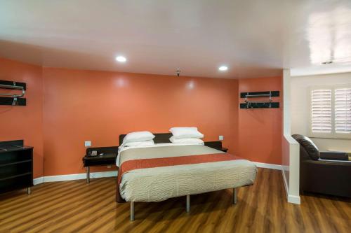 a bedroom with a bed with an orange wall at Motel 6 Monterey Park in Monterey Park