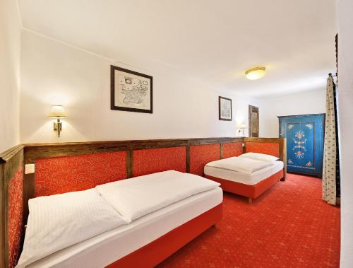 two beds in a room with red carpet at Hotel Konvice in Český Krumlov