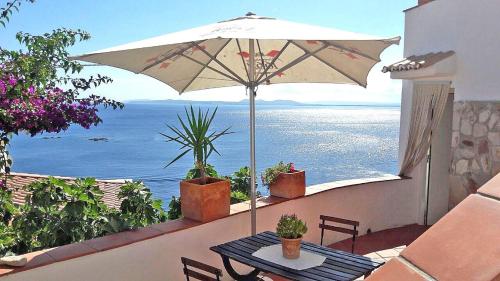 a table with an umbrella on a balcony with the ocean at Splendido studio, vista mare, a 5mn dalla spiaggia - Casa ArteVida in Roses