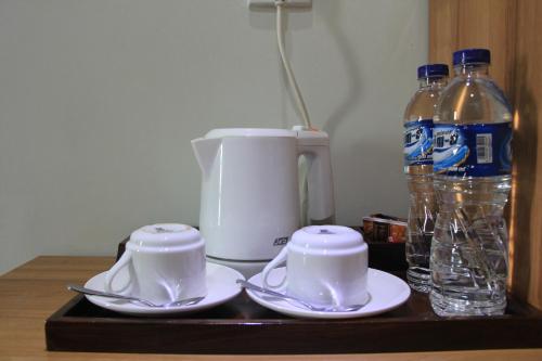 a tray with two cups and a coffee maker and bottles of water at Hotel Namira Syariah Pekalongan in Pekalongan