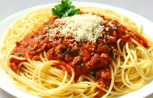 a plate of spaghetti with meat sauce and cheese at Hotel Namira Syariah Pekalongan in Pekalongan