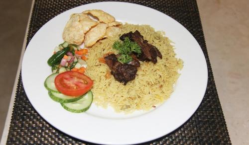 a plate of food with rice and vegetables on a table at Hotel Namira Syariah Pekalongan in Pekalongan