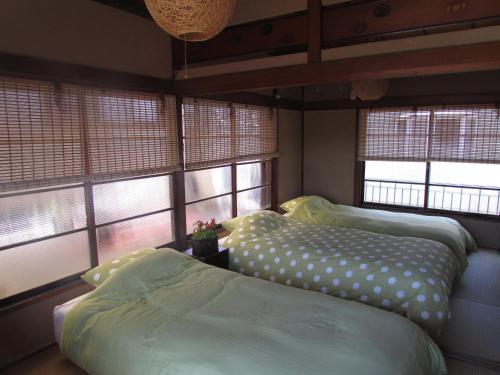 two beds in a room with two windows at ゲストハウス杉田 古民家貸切の完全プライベート空間 杉田駅徒歩2分 セルフチェックイン in Yokohama