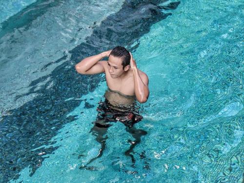 a man in the water in a swimming pool at Grand Livio Kuta Hotel in Legian