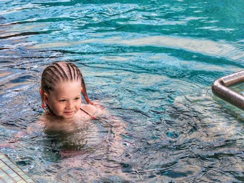 a young girl swimming in a swimming pool at Grand Livio Kuta Hotel in Legian