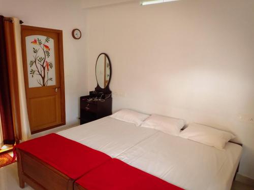a bedroom with a bed with a red and white blanket at Mountain Breeze Villa and Homestay in Idukki