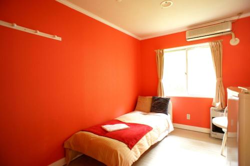 a bedroom with orange walls and a bed with a window at Karuizawa Pension Sato no Nukumori in Karuizawa