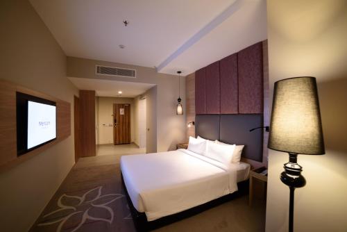 a hotel room with a bed and a lamp at Mercure Selangor Selayang in Batu Caves