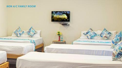 a room with three beds and a tv on the wall at Blue Ocean Sands - On the Beach in Kumta