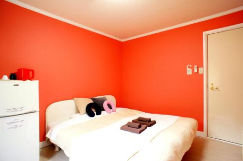 a bedroom with orange walls and a white bed at Karuizawa Pension Sato no Nukumori in Karuizawa