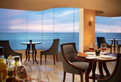 a restaurant with a table and chairs with a view of the ocean at Taj Samudra, Colombo in Colombo