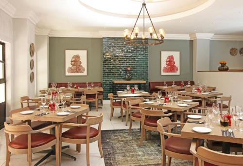 a restaurant with wooden tables and chairs and a fireplace at Hollow on the Square City Hotel in Cape Town