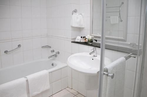 a white bathroom with a sink and a bath tub at Hollow on the Square City Hotel in Cape Town