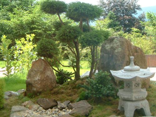 a garden with a stone birdbath and trees and rocks at Hotel Brunnenhof in Bayerisch Eisenstein