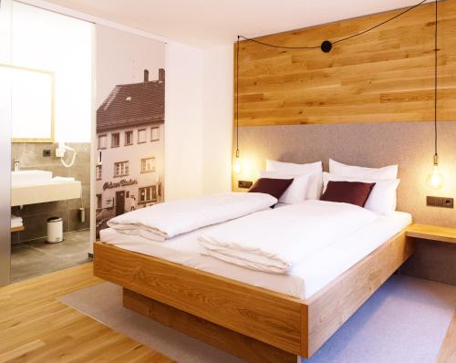 a bedroom with a large bed with a wooden headboard at Stadthotel Kachelofen in Krumbach