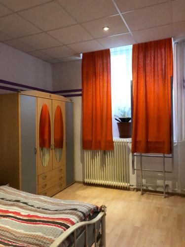 een slaapkamer met oranje gordijnen, een bed en een raam bij Munich Apartment Harras (Souterrain) in München