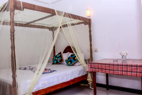 1 dormitorio con cama con dosel y mesa en Lilac Garden Mirissa, en Weligama