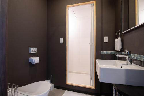 a bathroom with a sink and a toilet and a mirror at Hirafu Tomten in Niseko